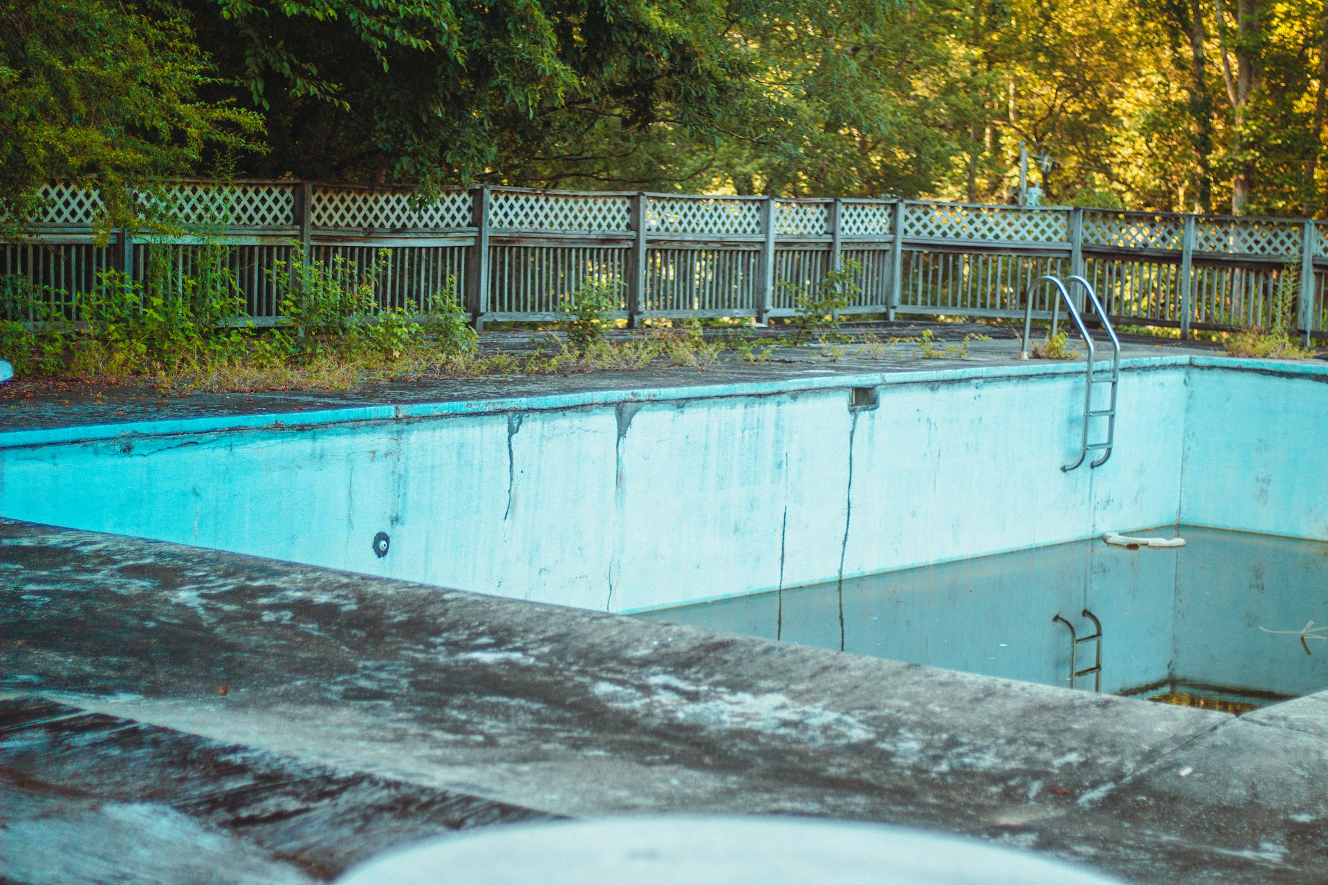 an empty swimming pool surrounded by a wooden fence